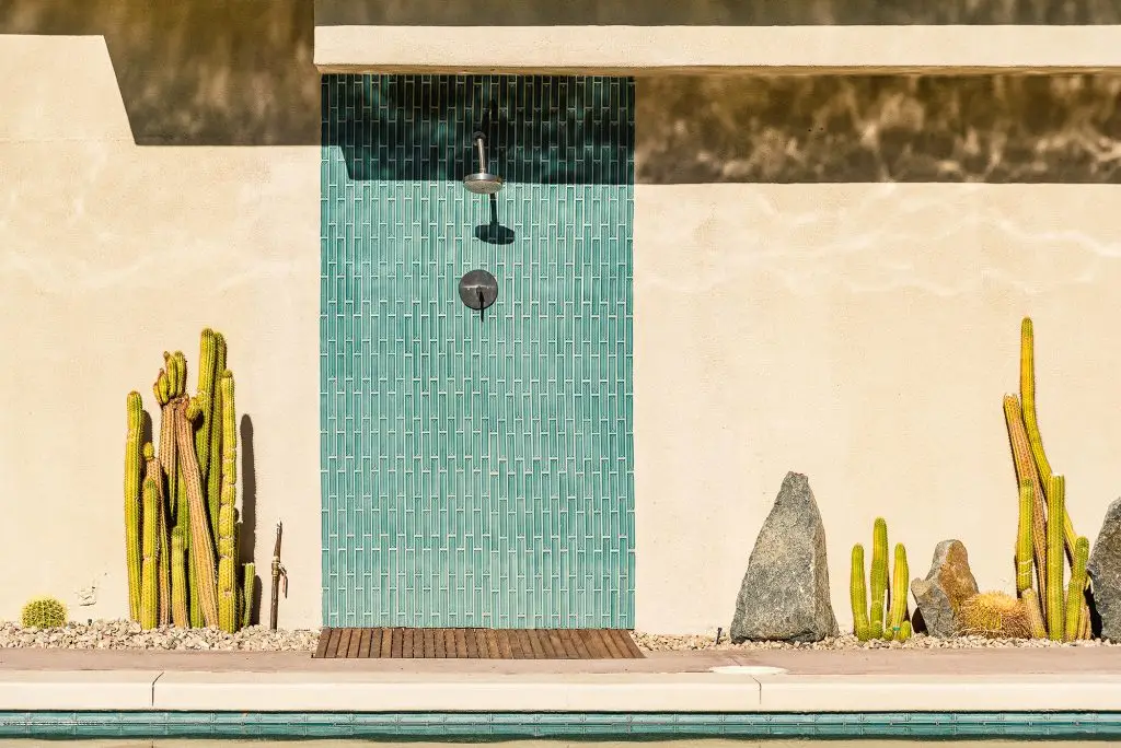 Outdoor shower with teal tile wall, surrounded by desert landscaping and cactus at Biskra House in Rancho Mirage, California.