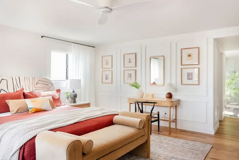 Spacious en-suite bedroom with coral and camel tones, rattan desk, and modern wall molding at Biskra House, Rancho Mirage.