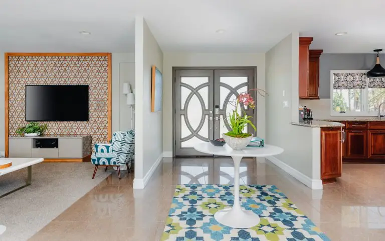 Stylish entryway with round table, patterned rug, and double gray doors at Biskra House, a vacation rental in Rancho Mirage, California.
