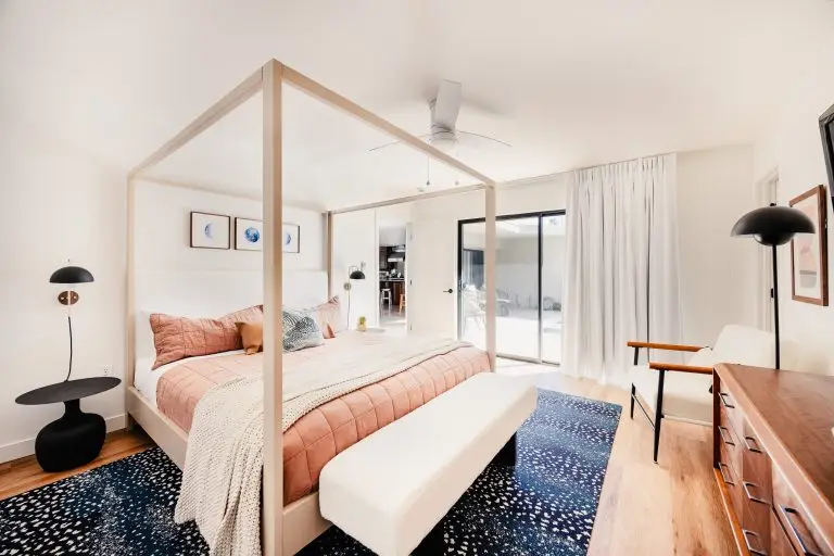 Spacious guest suite with modern four-poster bed, textured rug, and neutral walls at Biskra House, a Rancho Mirage vacation rental.