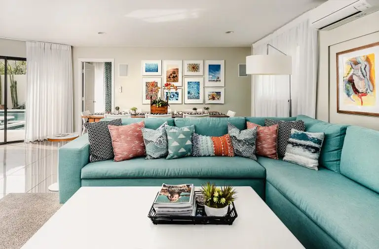 Open living area with teal sectional, coral pillows, and wall of framed desert and poolside art at Biskra House, Rancho Mirage, CA.