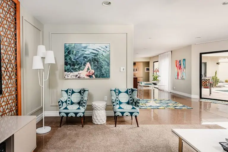 Mid-century inspired sitting area with teal patterned chairs and colorful modern art leading to pool patio at Biskra House.
